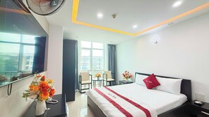 A hotel room with a bed, bedside table, and a desk with a fan and flowers. - Bien Sao Hotel Duong Quang Ham (Ho Chi Minh City)