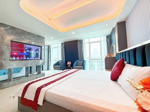 A modern hotel room with a large bed, a flat-screen TV mounted on a marble wall, and a city view through the windows. - Bien Sao Hotel Duong Quang Ham (Ho Chi Minh City)