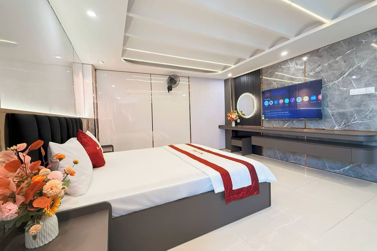 Ein modernes Hotelzimmer mit einem großen Bett, einem an der Wand montierten Fernseher und einer Marmor-Akzentwand.
