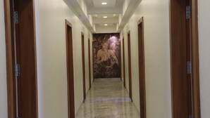 A corridor with marble flooring, wooden doors, and a mural on the wall. - Hotel Mayur Residency (Khuldabad)