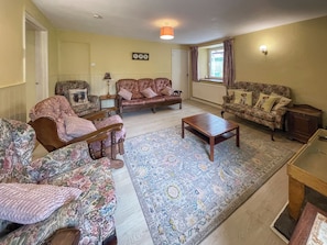 A living room with floral-patterned sofas, a wooden coffee table, and a patterned rug. - Hafod Fach - UKC6956 (Moylegrove near Ceibwr Bay)