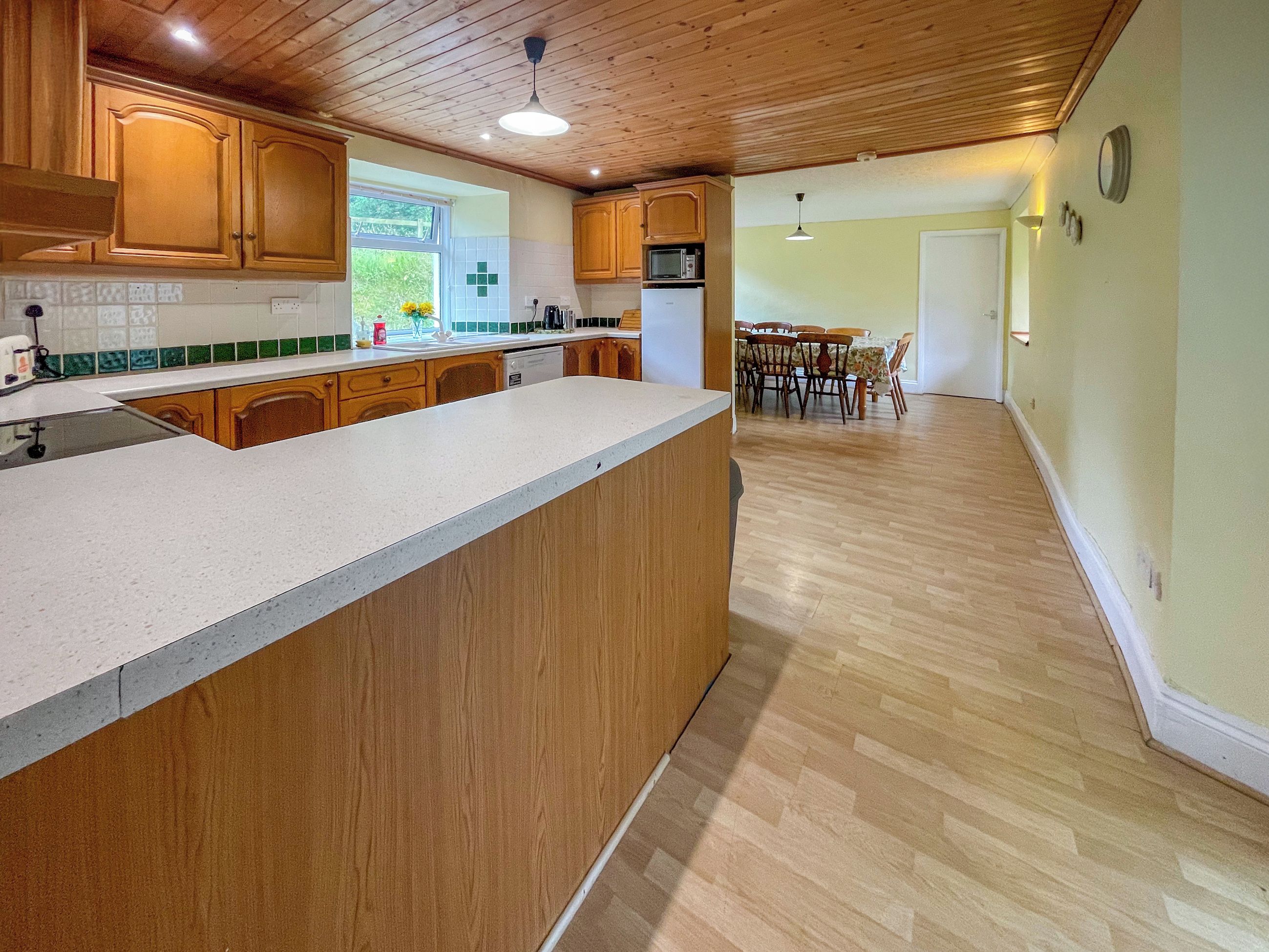 Une cuisine spacieuse avec des meubles en bois, un grand îlot central et un coin repas comprenant une table et des chaises.
