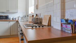 A modern kitchen with white cabinets, a microwave, toaster, and wooden countertop. - Pheasant Pens 1 - UK50187 (Llandenny, near Usk)