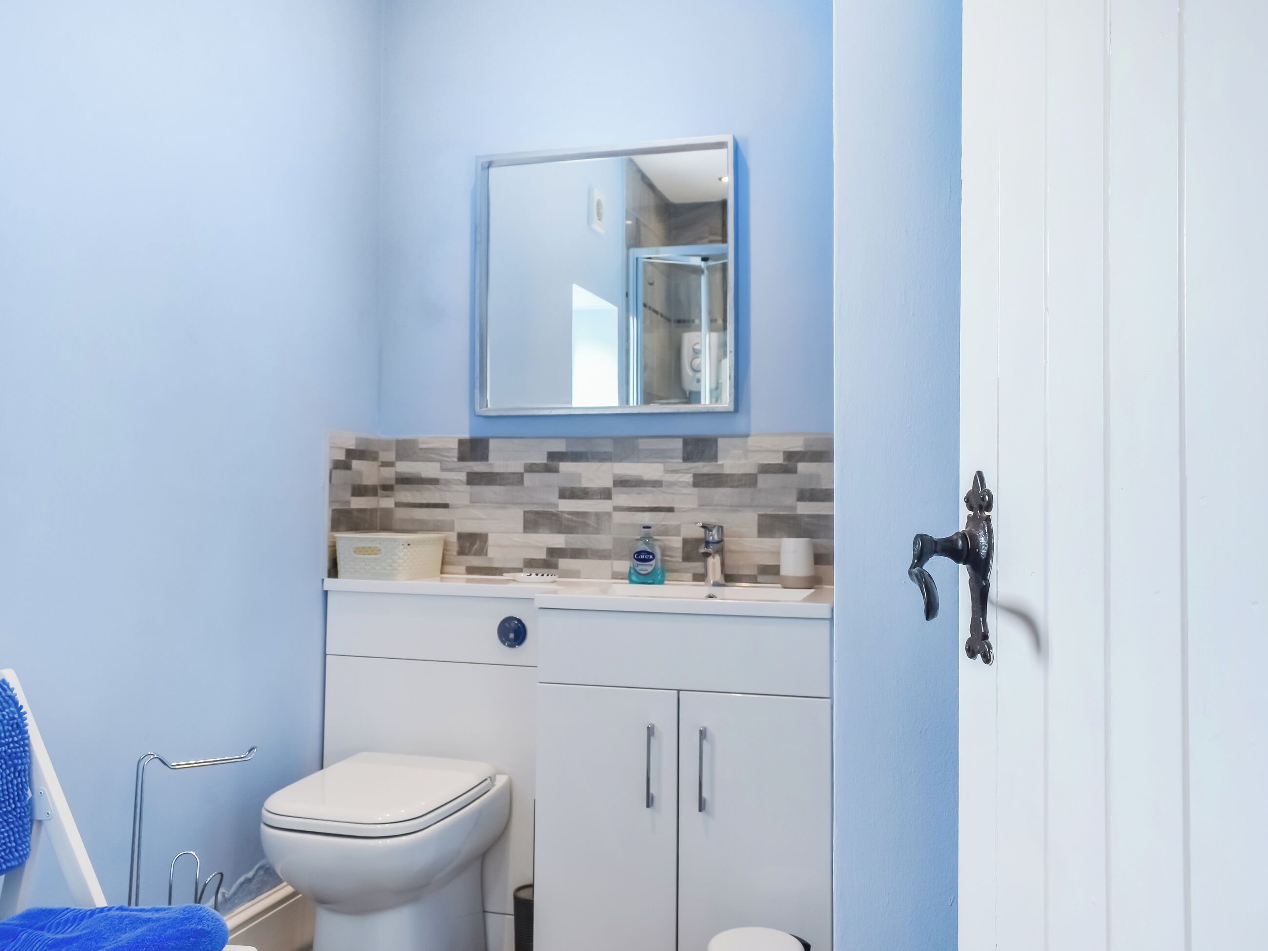 A bathroom with a toilet, sink, and mirror.