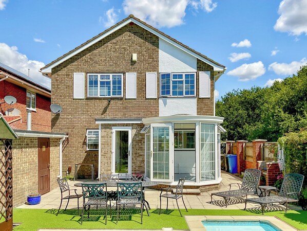 A two-story house with a patio area, a pool, and a conservatory. - 4 bedroom accommodation in Poole (Poole)