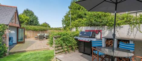 A backyard with a barbecue area, a wooden deck, and a patio with outdoor furniture.