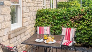 A stone wall, a glass table, two striped chairs, and a green hedge. - 3 bedroom accommodation in Helmsley (Helmsley)