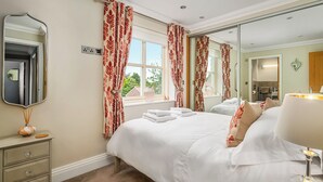 A hotel room with a large bed, a dresser, a mirror, and a window with curtains. - 3 bedroom accommodation in Helmsley (Helmsley)