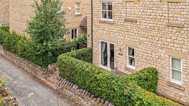 A stone building with a tiled roof, a stone wall with a stone staircase, and a hedge along the side of the road. - 3 bedroom accommodation in Helmsley (Helmsley)