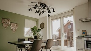 A modern kitchen with a dining area, featuring a large window, a hanging light fixture, and a view of the neighborhood. - Modern apartment with free view over the water (Uitgeest)