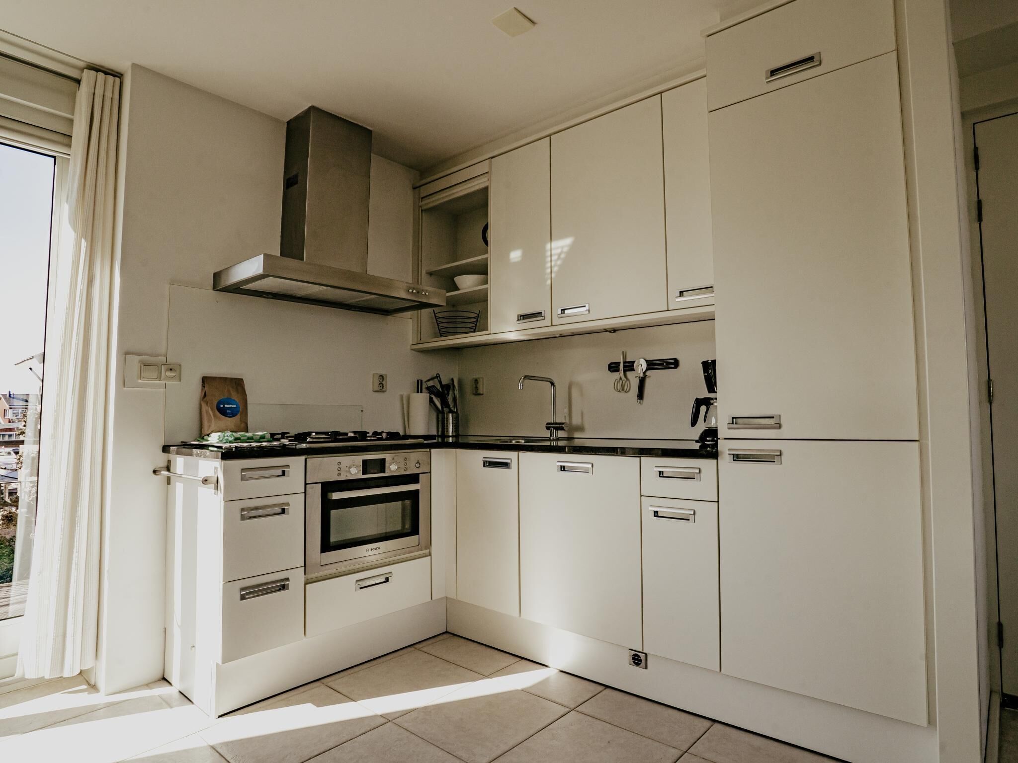 Une cuisine moderne avec des meubles blancs, une cuisinière, un four et un évier.