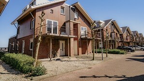 A modern residential building with a brick facade, multiple balconies, and a clear sky. - Modern apartment with free view over the water (Uitgeest)