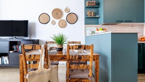 A modern kitchen with teal cabinetry, a wooden dining table with chairs, and a TV in the background. - Modern 2-bedroom apartment with pool (Costa Adeje)