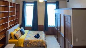 Une chambre d’hôtel avec un grand lit, un ventilateur de plafond, une armoire et une bibliothèque.