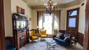 Un salon spacieux avec une cheminée, des fauteuils jaunes, un canapé bleu et un lustre.