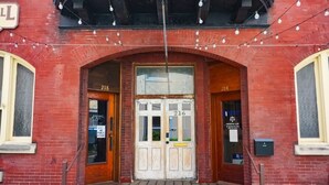 Un bâtiment en briques rouges avec deux portes numérotées, les numéros 218 et 216, et une entrée centrale.