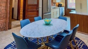 Un coin repas avec une table ronde, des chaises bleues et une lucarne au plafond.