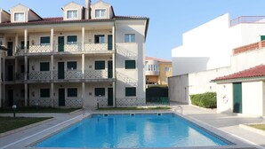 A multi-story residential building with a swimming pool in front.