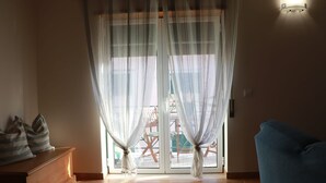A room with a sliding glass door, a blue sofa, and a wooden cabinet.