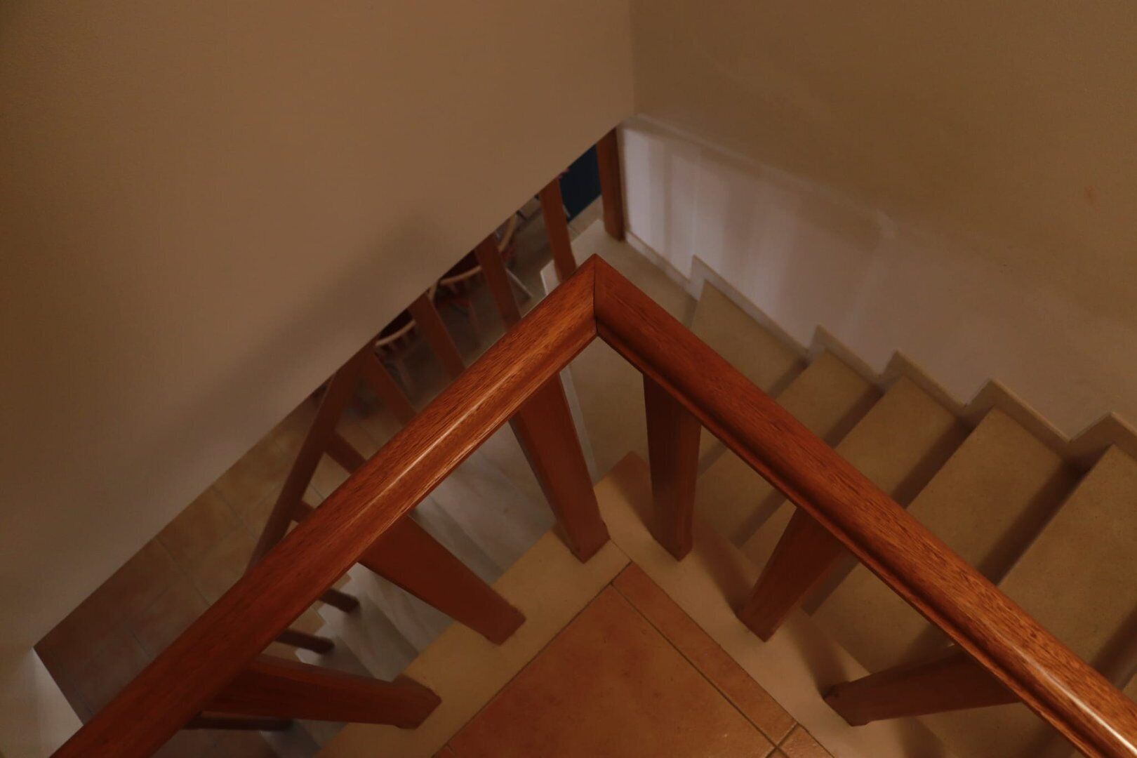 Una escalera de madera con barandilla y paredes color crema.