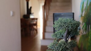 A hallway with a bonsai tree and a painting on the right.