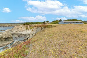 Et kysthus med en græsplæne og en klippe med udsigt over havet.