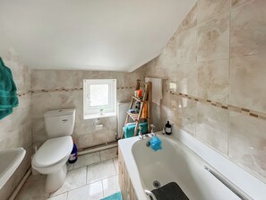 Une salle de bain équipée de toilettes, d’un lavabo, d’une baignoire et d’une fenêtre.