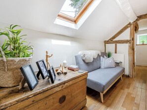 A cozy room with a loft bed, a wooden dresser, a grey sofa, and a skylight. - 4 bedroom accommodation in Welshpool (Welshpool)