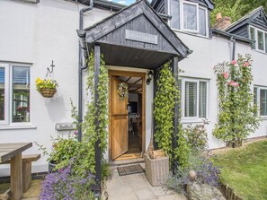A quaint building with a wooden entrance, a sign reading "PEN-Y-GROES," and a small porch area with hanging flower baskets. - 4 bedroom accommodation in Welshpool (Welshpool)