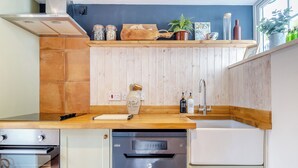 Een moderne keuken met houten aanrecht, een ingebouwde oven en een vaatwasser.