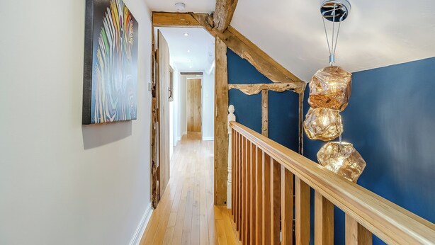 Een gang met houten vloer, een blauwe muur en een houten leuning.