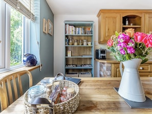 Eine Küche mit einem Holztisch, einem Bücherregal und einer Blumenvase.