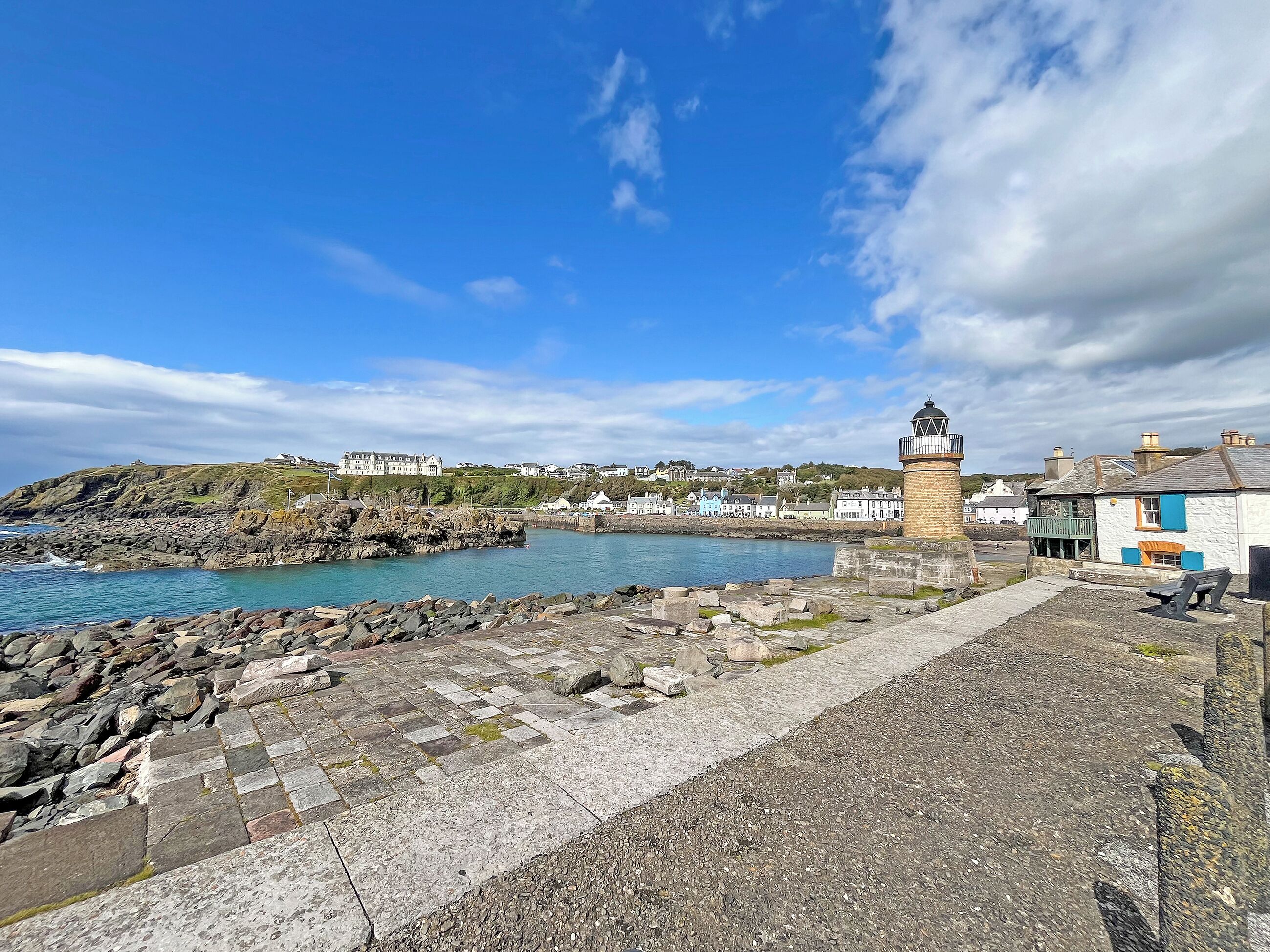 Une ville côtière dotée d’un phare imposant, d’une côte rocheuse et de bâtiments qui bordent la mer.