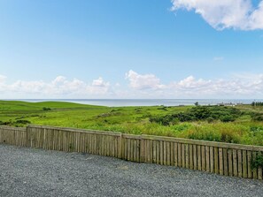A coastal landscape with a wooden fence and a gravel path.