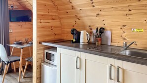 A compact kitchen with wooden walls, a microwave, a sink, and a dining area with a table and chairs.