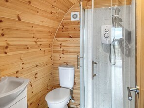 Ein kleines Badezimmer in einer Holzjagdhaus-ähnlichen Hütte, mit Toilette, Waschbecken und Dusche.