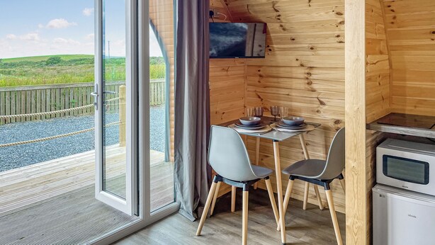 A wooden cabin with a dining area, a television, and a kitchenette.