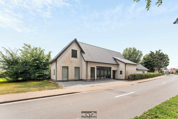 Ein modernes, zweistöckiges Haus mit Satteldach, großen Fenstern und einer Garagentür.