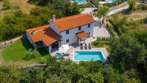 Une maison à deux étages avec une piscine et un patio couvert.