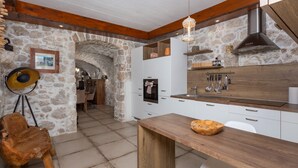 A kitchen with stone walls, wooden beams, a hanging light fixture, and a rustic wooden table. - Villa Mariva residence Crikvenica by Villas Guide (Tribalj)