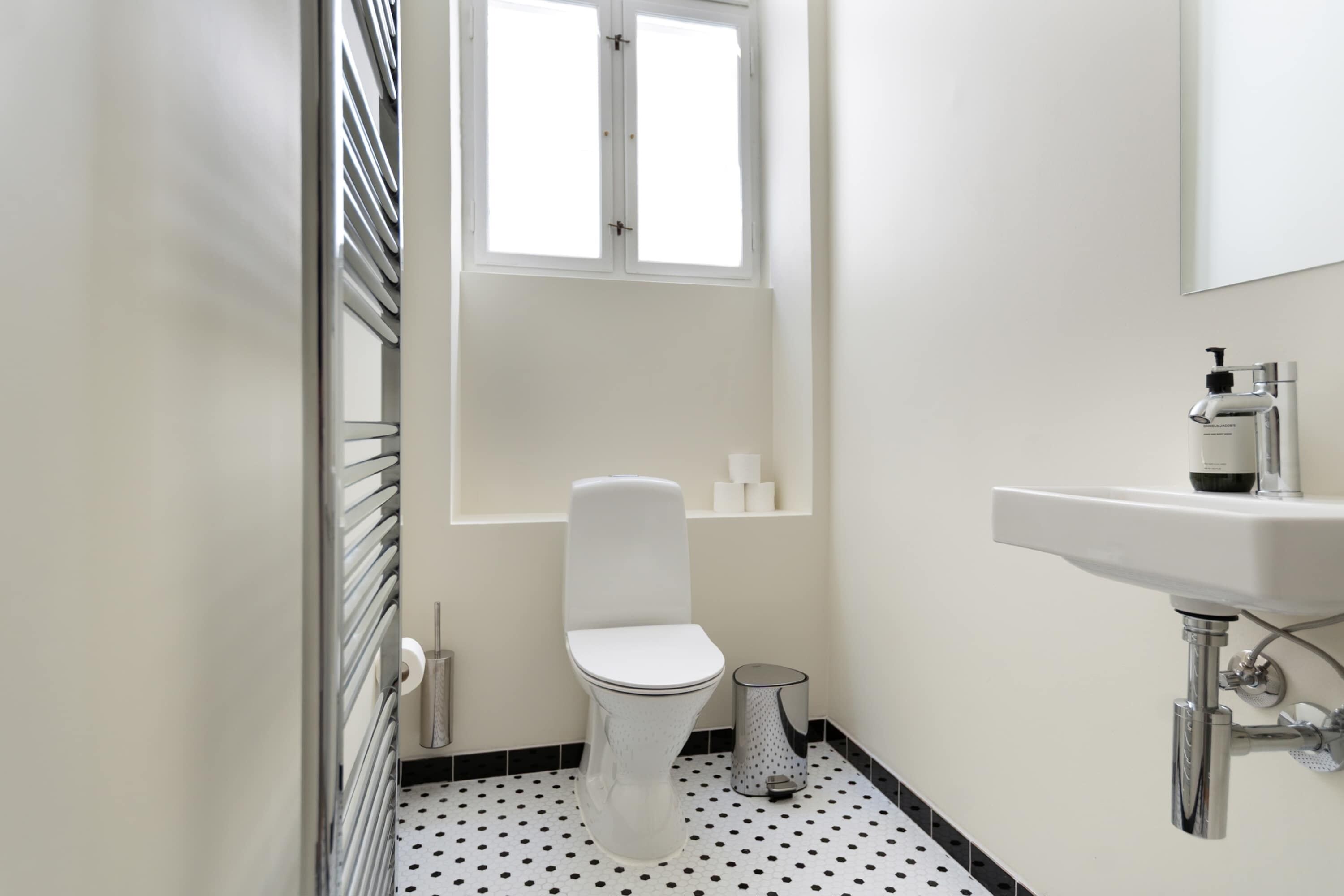 A small, modern bathroom with a toilet, a sink, and a window.