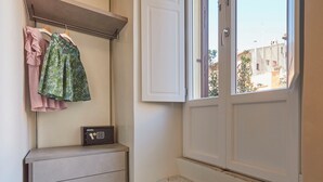 Una habitación pequeña con armario, caja fuerte y ventana con vistas a edificios.