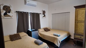 A room with two beds, a desk, an air conditioner, and a wardrobe. - Loft Los Pinos (Monterrey)
