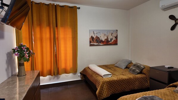 A bedroom with a bed, a nightstand, a painting, and a window with curtains. - Loft Los Pinos (Monterrey)