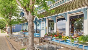 A cafe with outdoor seating, a large tree, and a view of the water. - Steps to Marina & Beach: Couple’s Cottage in Pepin (Pepin)