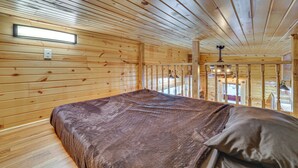 A wooden cabin interior with a bed, a ceiling light, and a window. - Steps to Marina & Beach: Couple’s Cottage in Pepin (Pepin)