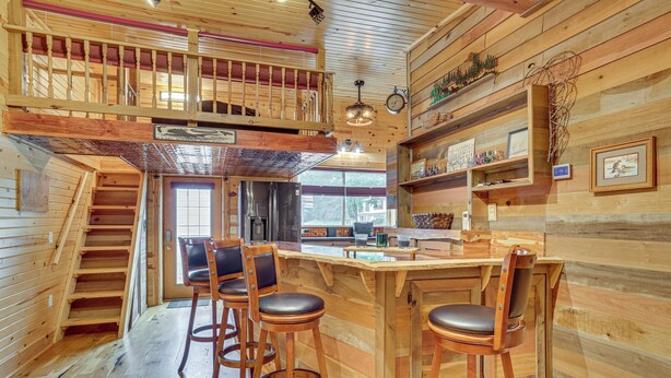 A wooden interior with a kitchen, bar area, and a staircase. - Steps to Marina & Beach: Couple’s Cottage in Pepin (Pepin)