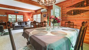 Een houten chalet van binnen, met een eettafel voor vier personen en houten stoelen eromheen.