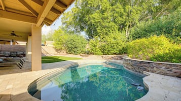 Piscina con pared de piedra y zona de terraza cubierta.