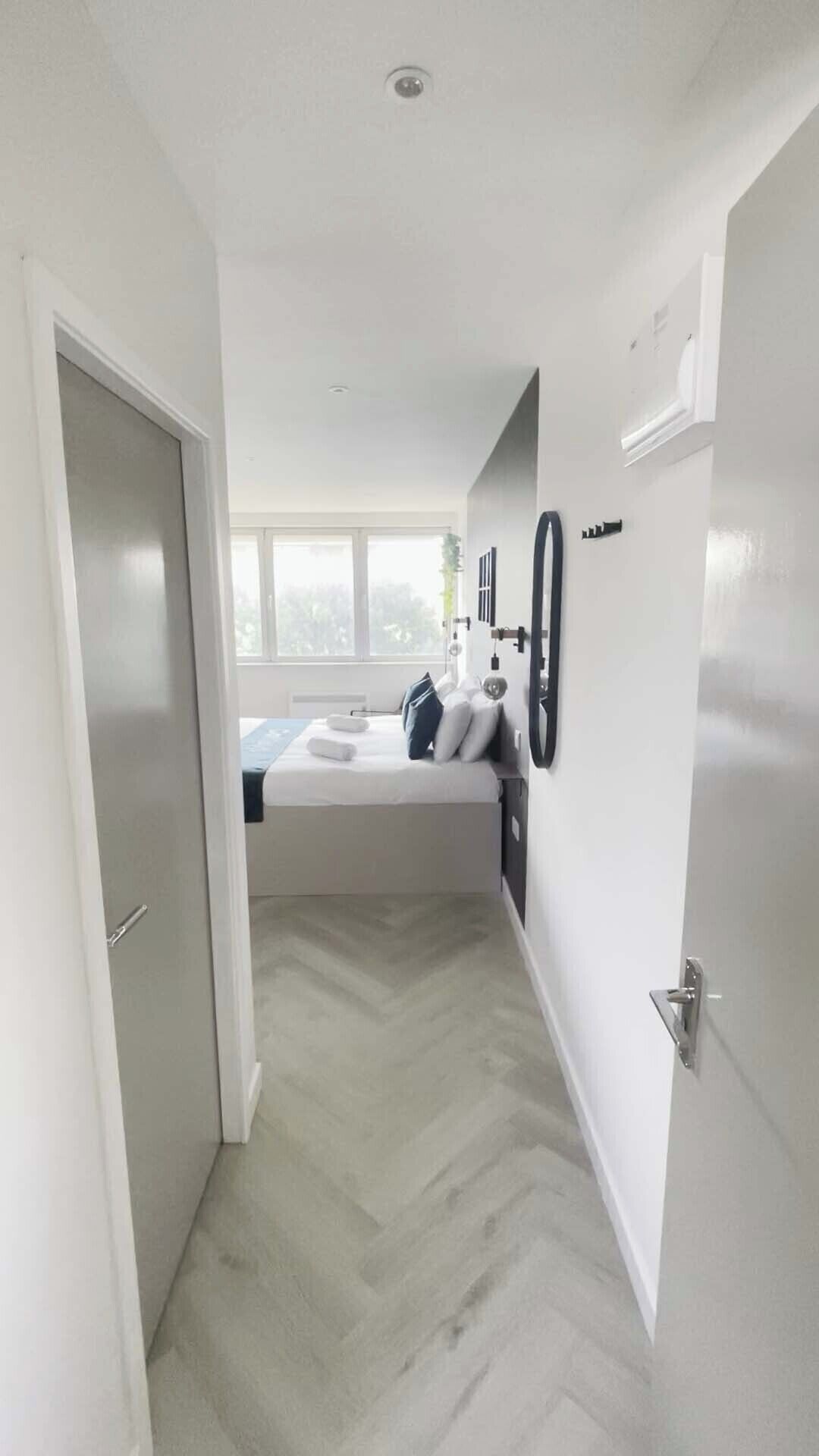 A modern, minimalist bedroom with a bed, bedside tables, and a window.